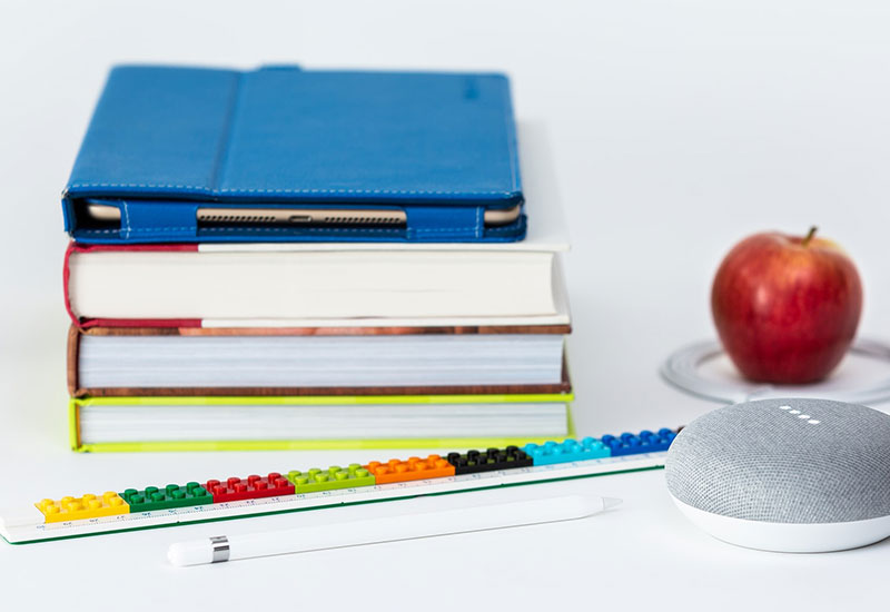 Stack of books, apple, and speaker