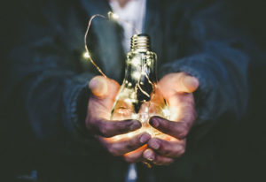 Hands holding a light bulb lit by string lights