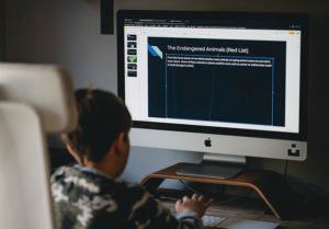 child sitting in front of computer screen revising text
