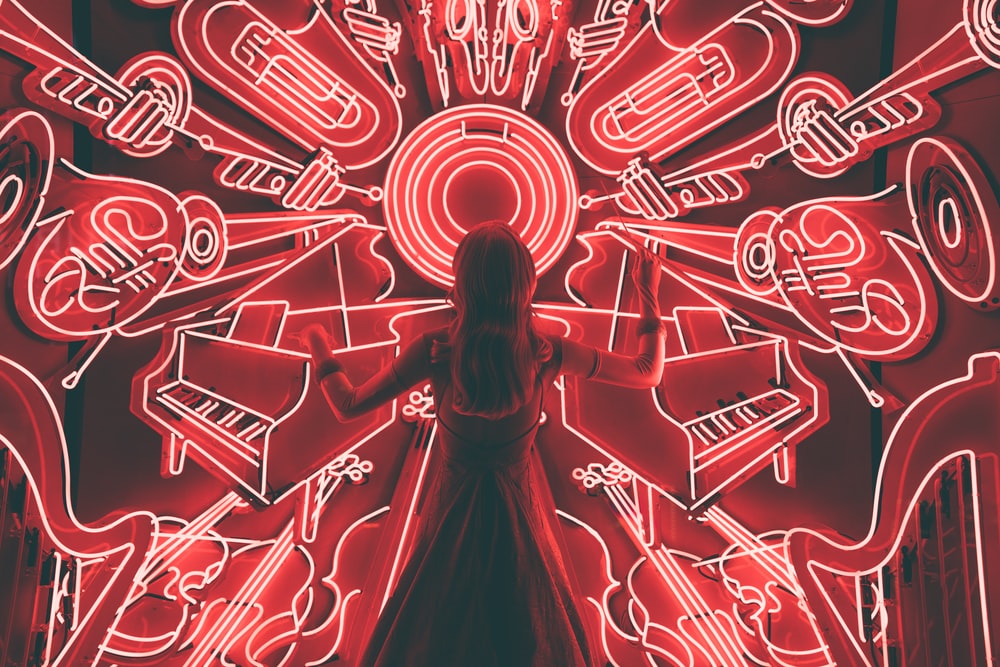 Person standing in front of neon lights in the shape of instruments