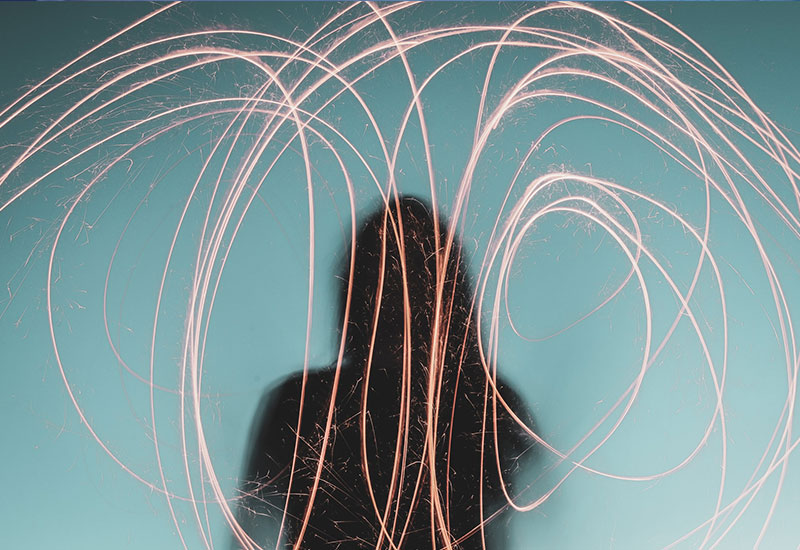 Light trails around a silhouette of a woman